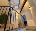 modern staircase in multistory house, two levels visible, white walls, wooden floor, glass banisters, open ceiling