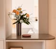 Vase with flowers on countertop, pillow, wooden plate, beige cupboards