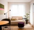 light walls, white sofa, round table, chair, side table, floor lamp, television, painting, pot plant, rug