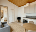 small cozy room with bed, couch, TV, small table, kitchen with sink, oven, microwave, open layout