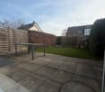 Rectangular paved terrace, table, hedge, and manhole