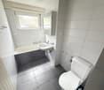 modern bathroom with white walls, tiled floor, bathtub, sink, and toilet