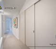 Empty hallway with white walls, tiled floor, sliding doors, and a framed picture on the wall.