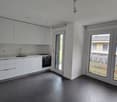 modern kitchen with white cabinets, black floor, sink, oven, sliding glass doors, advertisement poster