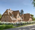 2 story house, brick, thatched roof, large windows, garden, bushes, road