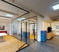 modern office with glass walls, wooden floor, white ceiling, blue cabinets, white table, coffee machine