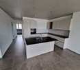 modern kitchen with white cabinets, black countertops, stainless steel faucet, tiled floor, open layout