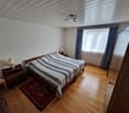 Bedroom with wooden floor, bed, nightstands, lamps, rug, window with curtains, wardrobe