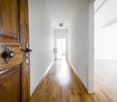 Empty hallway with wooden floor, white walls, and a door.