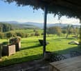 wooden deck, outdoor table, chairs, potted plants, swing, green lawn, distant mountains