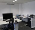 An office with two desks, a computer monitor, keyboard, mouse, and a printer.