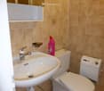 Bathroom with beige tile walls, a sink, a toilet, and a washing machine.