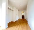 empty hallway, wooden floor, white walls, large mirror, closet, doors to different rooms