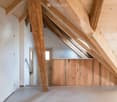 ample wooden beams, wooden ceiling, white walls, wooden floor, a window