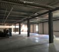 Large open space with high ceilings, concrete floor, and metal support beams. The space appears to be empty and ready for use as a warehouse or storage facility.