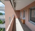 Balcony with tiled floor, pink exterior walls, large windows, outdoor storage unit
