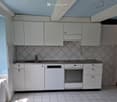 kitchen with white cabinets, tiled walls, gas stove, oven, dishwasher, radiator, window, blue wall