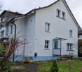 White building, blue and white trim, double storey, glass door, bench