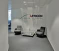 Modern office with gray chairs, glass table, white walls, TRICON branding, minimalistic design