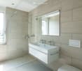 white sink, white toilet, white tiled wall, mirror, glass shower enclosure