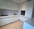 Modern kitchen with white cabinets, tiled floor, kitchen island, gas stove, sink, built-in oven