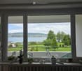 Window with view of lake, balcony with railing, potted plants on the windowsill