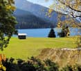 green grass, small wooden house, lake, mountains, trees