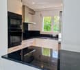 Kitchen: black countertops, white cabinets, black oven, microwave, sink, window