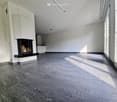 empty room, white walls, black fireplace, gray tile flooring, white cabinetry, large windows