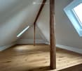 Empty attic room, wooden floor, two wooden pillars, two skylights