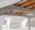 exposed wooden beams, white walls, windows, radiators