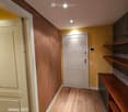Corridor with wooden floor, yellow walls, wooden cabinets, entry door, recessed ceiling lights.