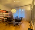 conference table, black mesh chairs, wooden parquet floor, white ceiling, light fixture, bookshelves with various books