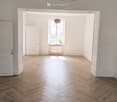 spacious room, hardwood herringbone flooring, white walls, doors, windows, ceiling lamp