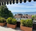 Balcony with wooden railing, view of the city, brown wooden planters, plants