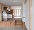 Kitchen area, stainless steel appliances, wooden cabinets, large windows, stairs