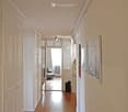 Hallway with white walls, wooden floors, and cabinets