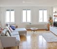 gray sofa, coffee table, tv, hardwood floor, white radiators, white walls, plants