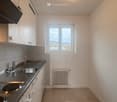 Empty modern kitchen, tiled backsplash, stainless steel countertop, silver sink with a faucet, heating radiator, window.