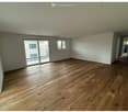 Empty room with hardwood floors, sliding doors, windows, white walls, and balcony