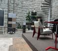 outdoor courtyard with stone wall, carpeted floor, table and chairs, spiral staircase, plants, cabinets