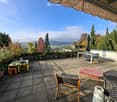 Terrace with tables, chairs, seating area, plants, umbrella, view of valley and mountains