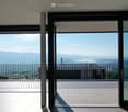 Balcony with metal railings, panoramic windows, view of the lake and mountains, tiled floor
