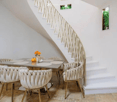 Dining room, wooden chairs, wooden table, white wall, spiral staircase,  small plant wall