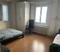 Bedroom with bed, chair, cabinet, windows, radiator