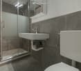 tiled floors, glass shower, toilet, sink with faucet