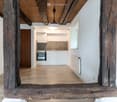 empty room, wooden beams, hardwood floor, white walls, small kitchen