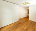 empty room with wooden floor, white walls, large closet, sliding door, open door leading to another room