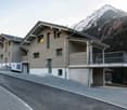modern design, wooden and gray materials, balcony, multiple windows, garage, snowy mountain background