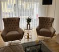 brown armchairs, coffee table, side table with vase, floor lamp, window with white curtains